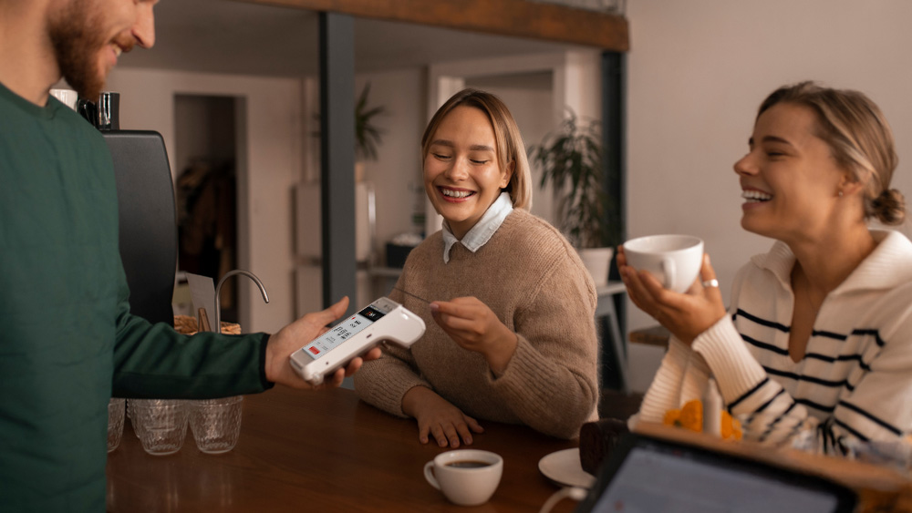 Waiter using PAX A920 PRO for contactless payment with customers in cafe lowest fees card machine