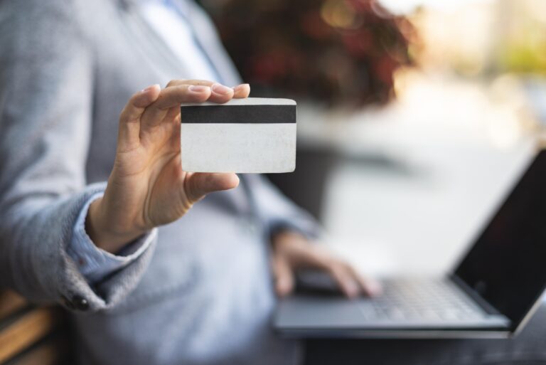 Person holding credit card using laptop for online payment processing UK business transaction