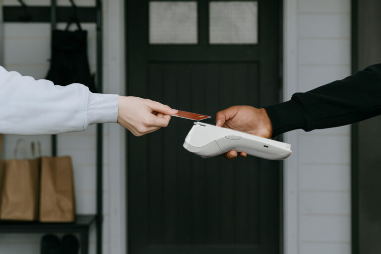 Small business owner processing contactless payment on modern card machine UK with customer tapping credit card