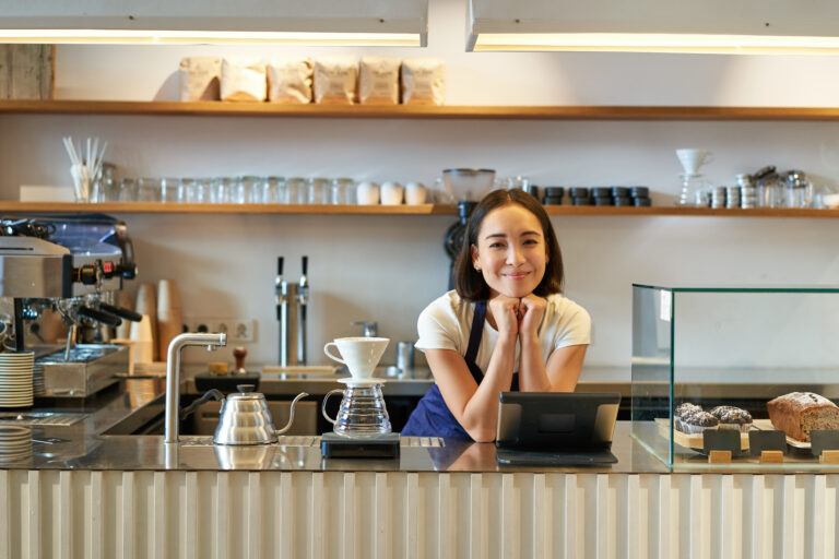 Waiter using EPOS integration UK tablet system at coffee shop counter for contactless payment processing