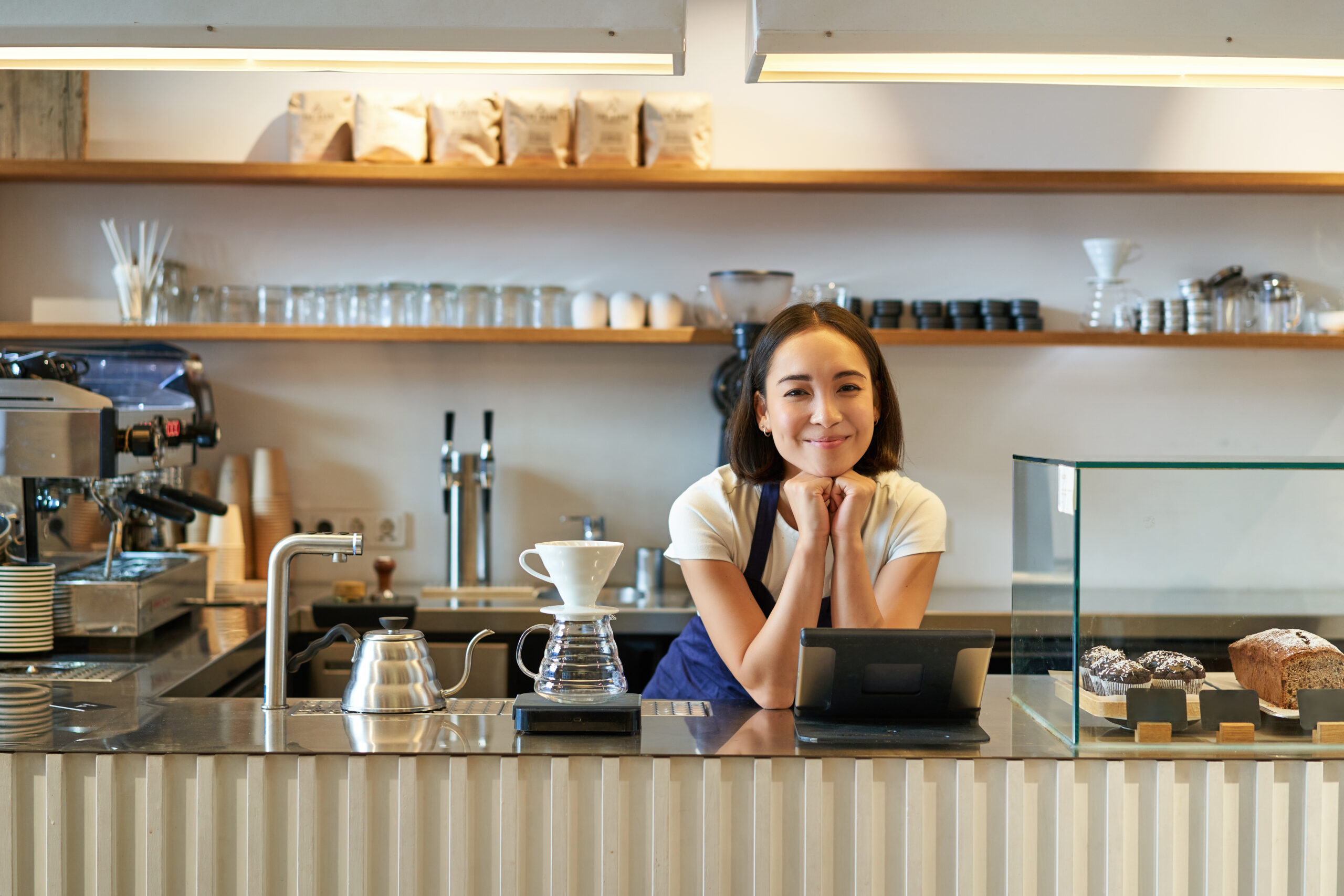 Waiter using EPOS integration UK tablet system at coffee shop counter for contactless payment processing