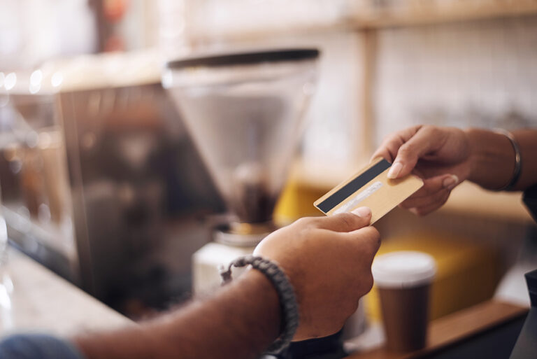 Customer handing over a card payment at a coffee shop counter with a UK payment provider