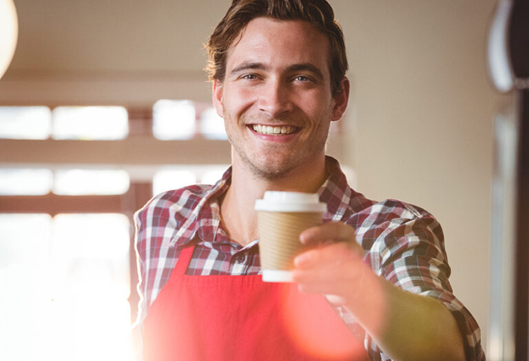 Male waiter handing over a takeaway coffee to a customer