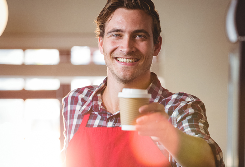 Male waiter handing over a takeaway coffee to a customer