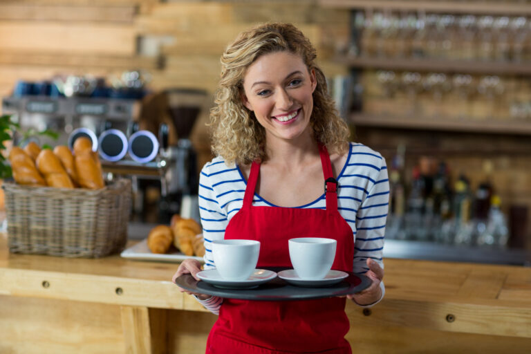 Female waiter holding a tray of coffees in a retail hospitality setting