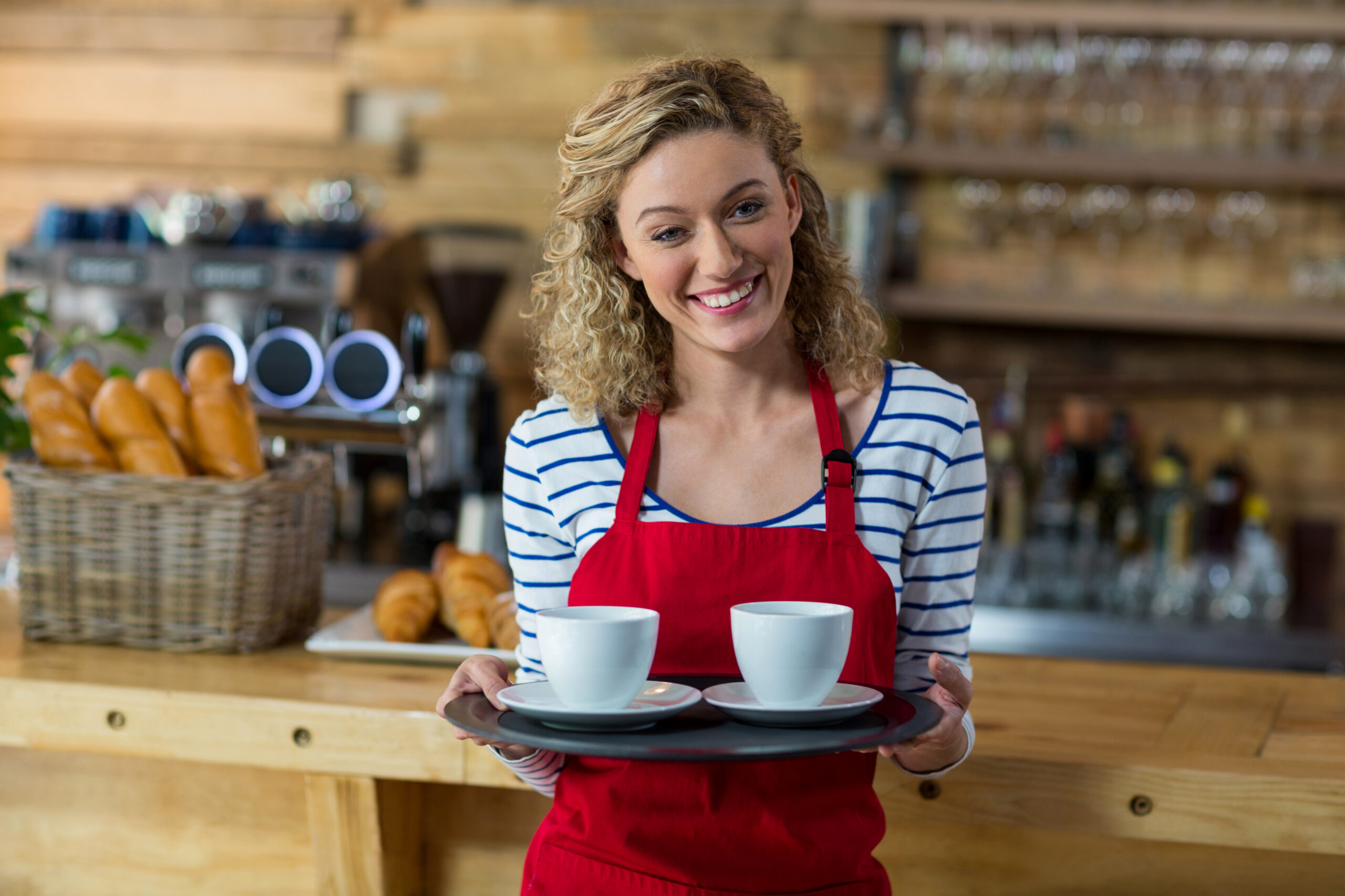 Female waiter holding a tray of coffees in a retail hospitality setting